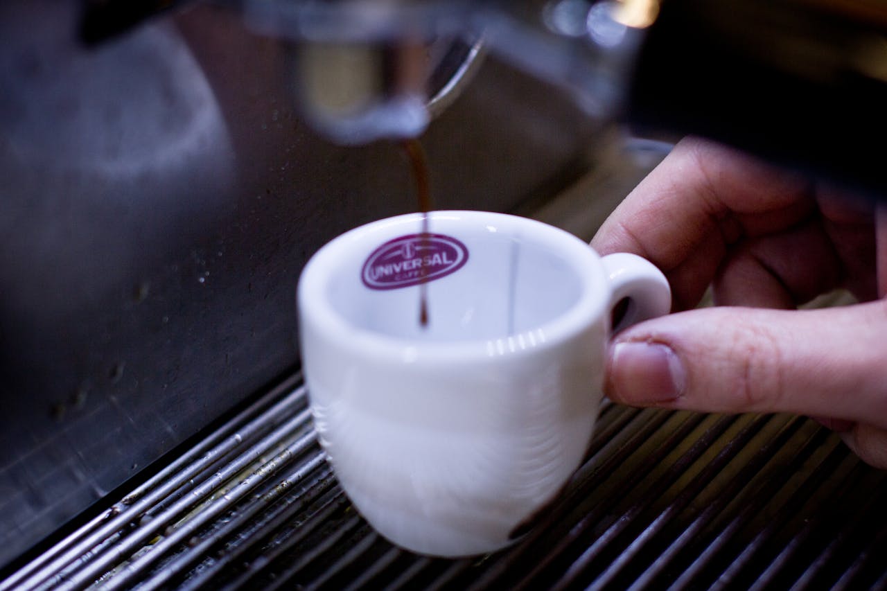 A detailed shot of espresso being poured into a white cup from a coffee machine.